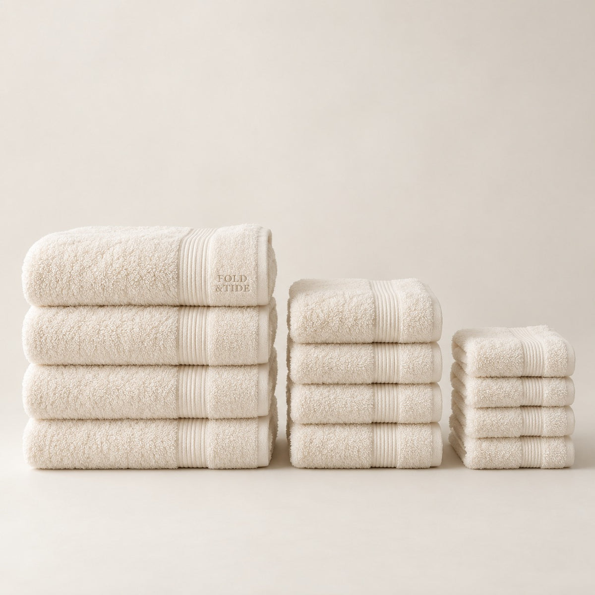 Twelve-piece ivory towel set design concept — four bath towels, four hand towels and four washcloths; not an approved physical product photograph